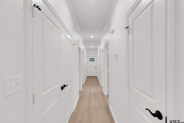 corridor featuring light wood-style floors, baseboards, ornamental molding, and recessed lighting