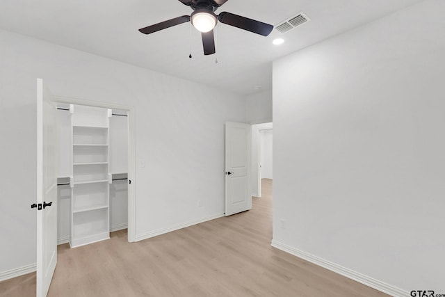 unfurnished bedroom featuring a spacious closet, light wood-style flooring, visible vents, and baseboards