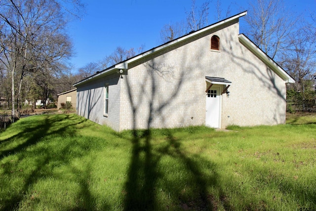 view of side of home with brick siding and a yard