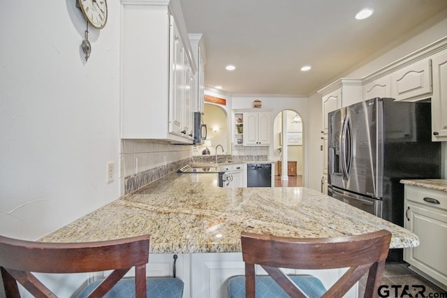 502 Northcreek Dr, Chandler, TX 75758 - kitchen featuring appliances with stainless steel finishes, arched walkways, a peninsula, tasteful backsplash, and a breakfast bar area