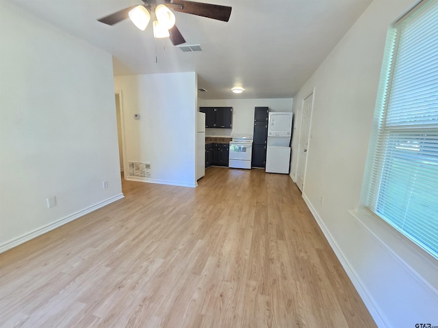 201 W Paschal St, Troup, TX 75789 - unfurnished living room featuring stacked washer / dryer, light wood-style floors, ceiling fan, and baseboards