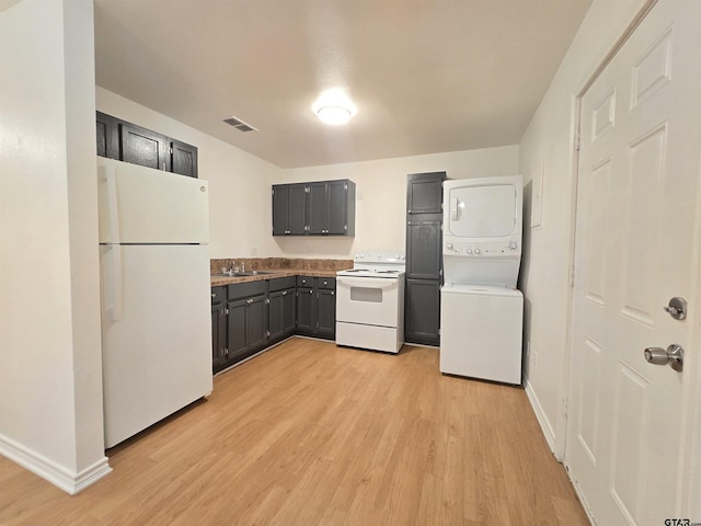 201 W Paschal St, Troup, TX 75789 - kitchen featuring white appliances, stacked washer and clothes dryer, a sink, light wood finished floors, and baseboards