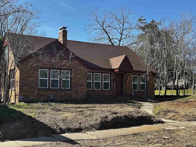 view of front of property with brick siding, a chimney, and a shingled roof