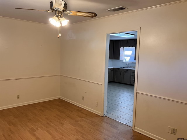 unfurnished room with sink, ornamental molding, hardwood / wood-style floors, and ceiling fan