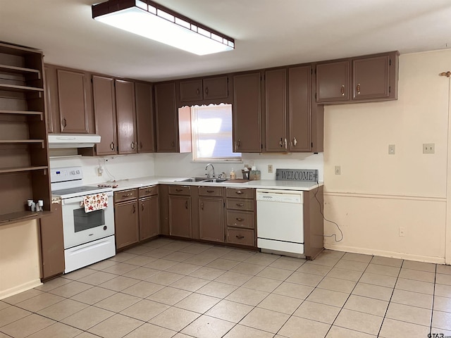 kitchen with dark brown cabinetry, sink, light tile patterned floors, and white appliances