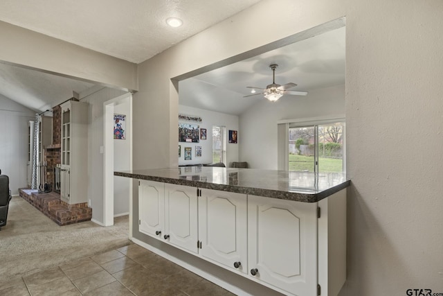 kitchen featuring lofted ceiling, light carpet, white cabinets, and ceiling fan