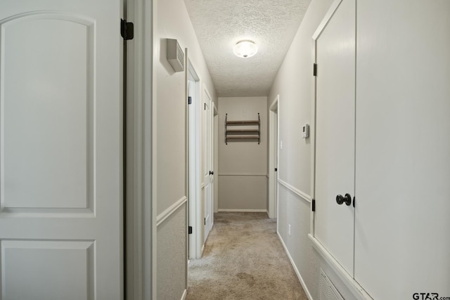 corridor featuring light colored carpet and a textured ceiling