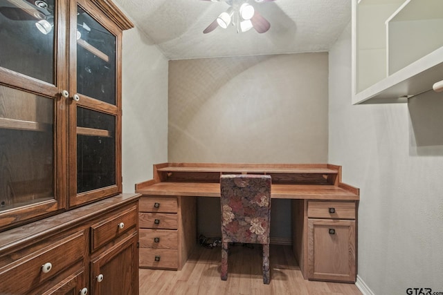 office space with ceiling fan, built in desk, and light wood-type flooring