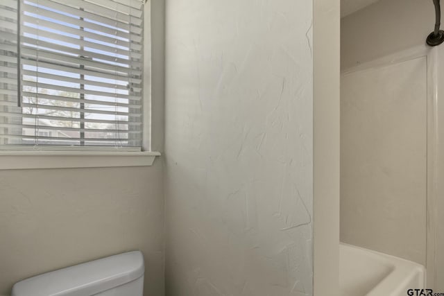 bathroom featuring a washtub and toilet