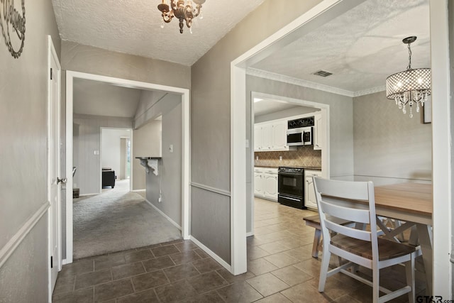 hall featuring an inviting chandelier, a textured ceiling, and carpet