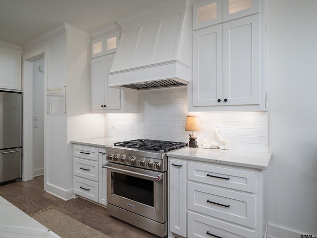 1555 Maple Crk, Tyler, TX 75703 - kitchen with stainless steel appliances, premium range hood, backsplash, dark wood-style flooring, and white cabinets