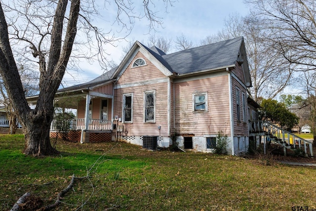 view of front facade with a front yard, covered porch, and central air condition unit