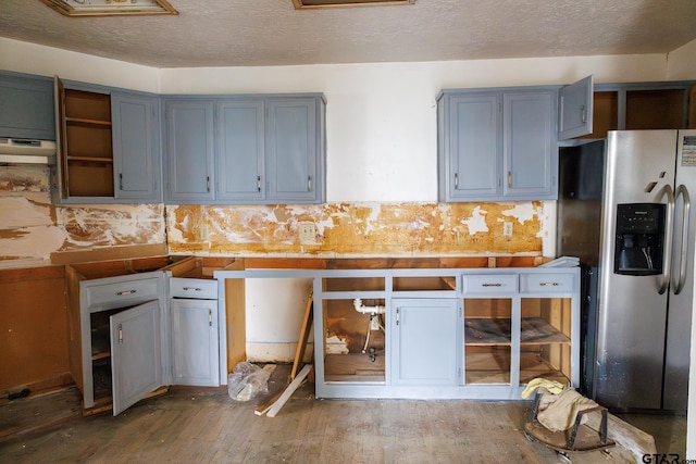 kitchen featuring stainless steel fridge with ice dispenser, range hood, tasteful backsplash, wood-type flooring, and a textured ceiling