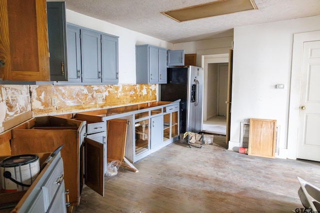 kitchen with stainless steel fridge with ice dispenser, a textured ceiling, decorative backsplash, and hardwood / wood-style floors