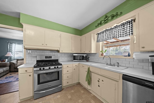 kitchen with tasteful backsplash, cream cabinets, stainless steel appliances, light wood-type flooring, and sink