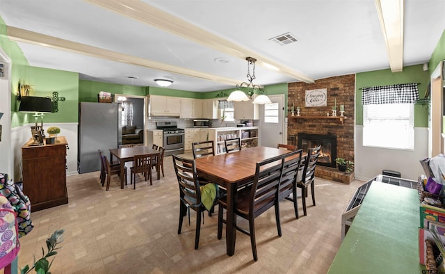 dining room featuring a fireplace, a wealth of natural light, and beamed ceiling