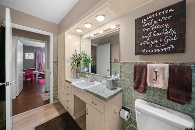 bathroom featuring tile walls, wood-type flooring, toilet, and vanity