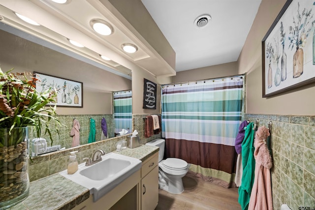 bathroom featuring hardwood / wood-style flooring, a shower with shower curtain, vanity, toilet, and tile walls