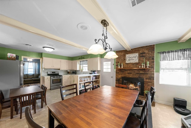 dining area with beamed ceiling, sink, and a brick fireplace