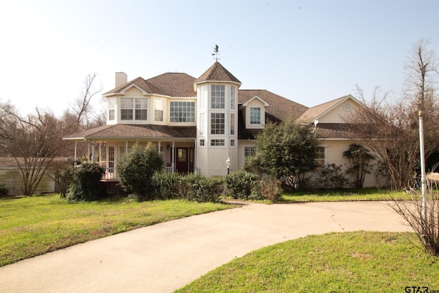 view of front of home featuring a front lawn, concrete driveway, and a chimney