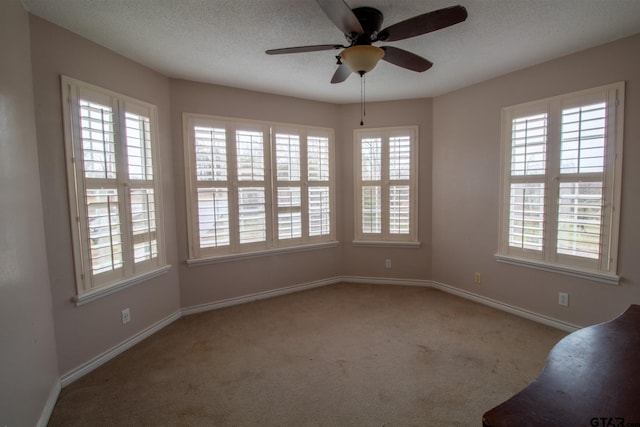 unfurnished room featuring baseboards, carpet flooring, a textured ceiling, and a ceiling fan