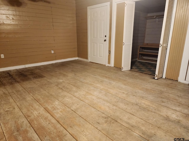 unfurnished bedroom with wooden walls and light hardwood / wood-style floors