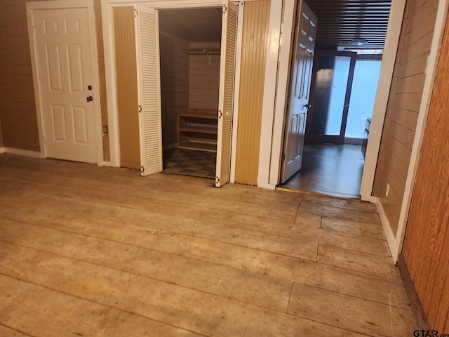 corridor with light hardwood / wood-style floors and wood walls