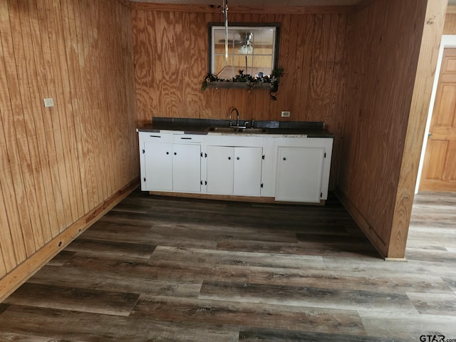 bar featuring sink, wood walls, white cabinetry, decorative light fixtures, and dark hardwood / wood-style flooring