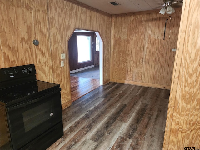 interior space featuring black range with electric stovetop, dark wood-type flooring, and wood walls