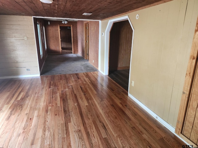 hallway with dark hardwood / wood-style flooring, wooden walls, and wooden ceiling