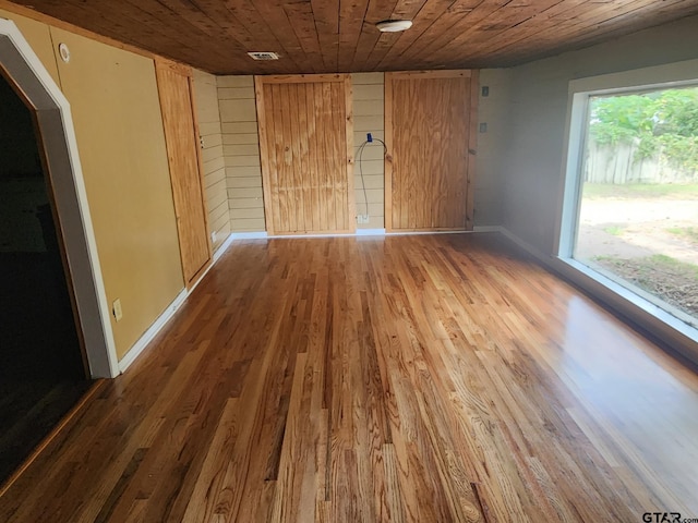 empty room with wood-type flooring, wood ceiling, and wood walls