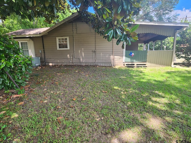 view of side of property featuring a yard and central AC