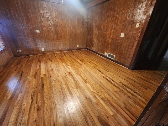 empty room with light hardwood / wood-style floors and wood walls