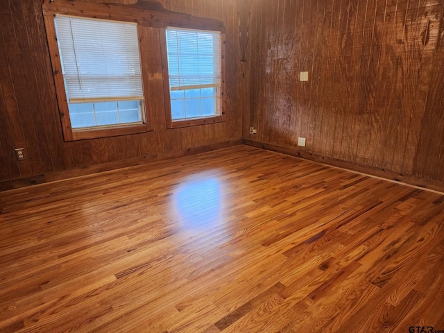 spare room featuring wooden walls and light wood-type flooring