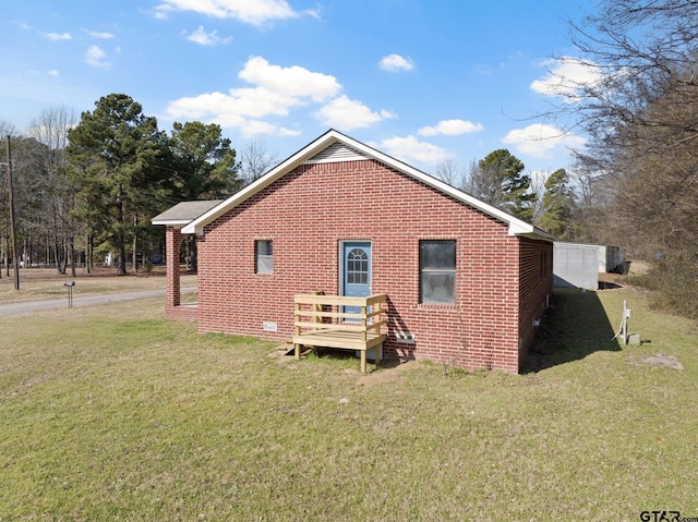 back of property featuring brick siding, a yard, and a wooden deck