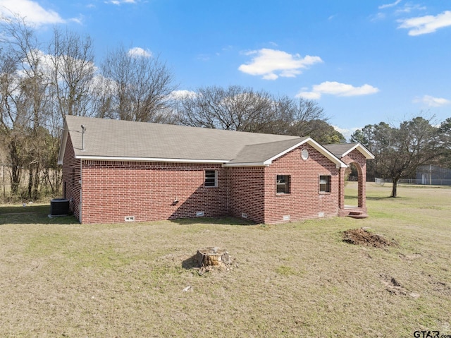 view of side of home with brick siding, a lawn, crawl space, and a shingled roof