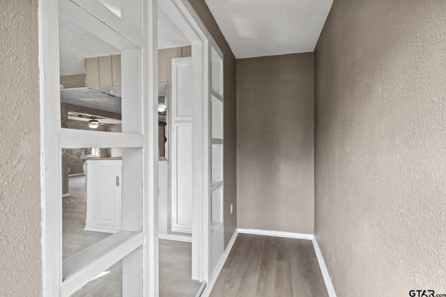 interior space featuring a textured wall, baseboards, and wood finished floors