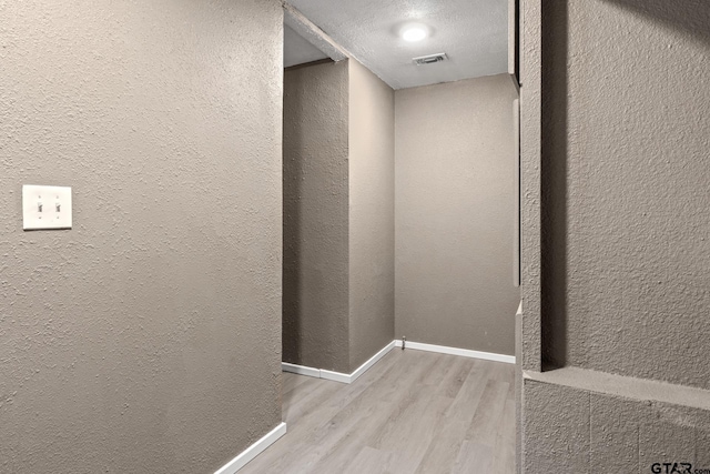 details featuring baseboards, a textured wall, wood finished floors, and visible vents