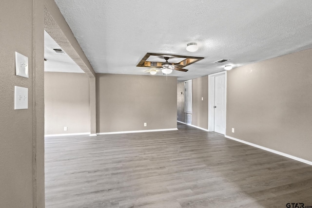empty room featuring baseboards, wood finished floors, and a textured ceiling