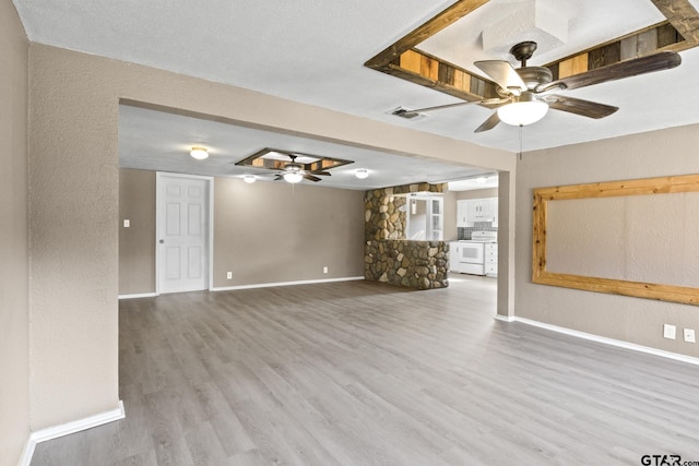 unfurnished living room featuring wood finished floors, visible vents, a ceiling fan, and baseboards