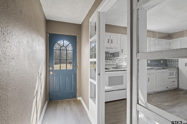 entryway featuring light wood-style flooring, a textured ceiling, and a textured wall