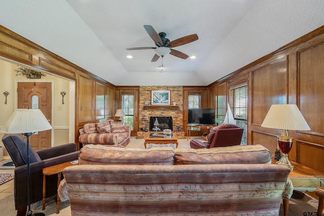 tiled living room with wooden walls, a brick fireplace, ceiling fan, and lofted ceiling