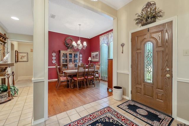 tiled foyer featuring an inviting chandelier and ornamental molding