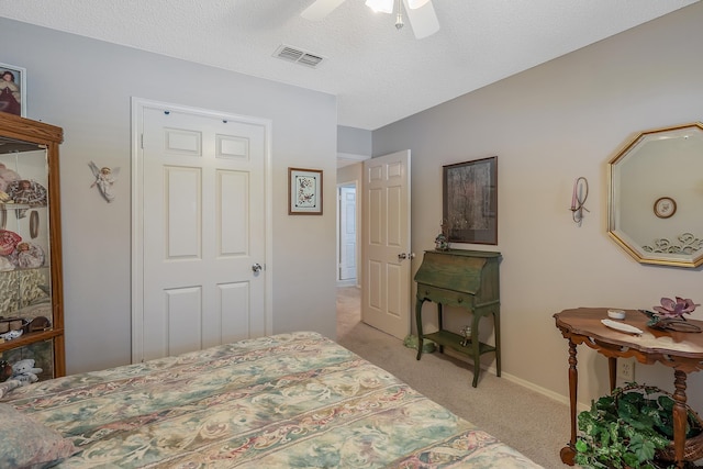 bedroom with a textured ceiling, ceiling fan, and light carpet