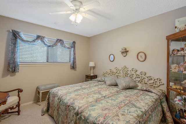 bedroom featuring a textured ceiling, light colored carpet, and ceiling fan