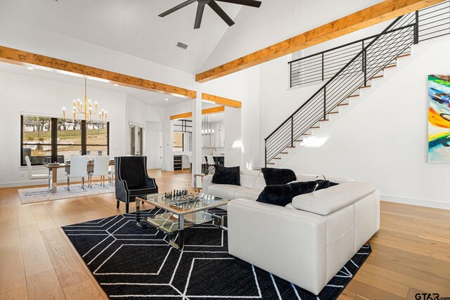 living room with stairs, high vaulted ceiling, light wood-style floors, and ceiling fan with notable chandelier