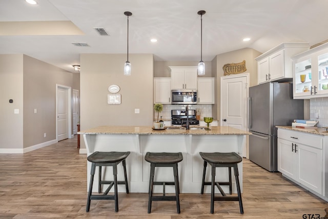 kitchen with white cabinetry, stainless steel appliances, and a center island with sink