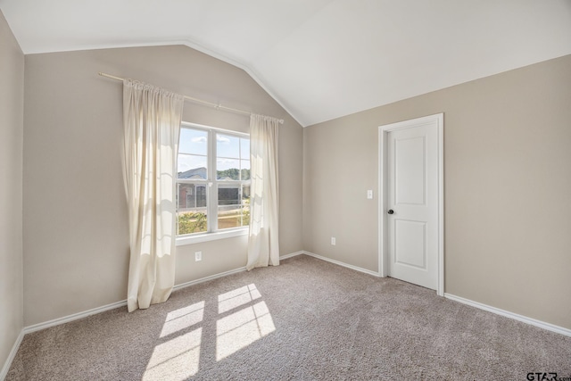 carpeted spare room with vaulted ceiling