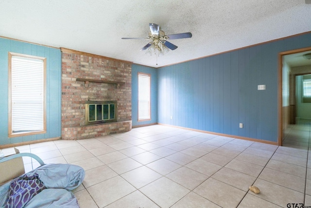 310 Windridge Rd, Palestine, TX 75801 - unfurnished living room featuring ceiling fan, tile patterned flooring, a textured ceiling, crown molding, and a fireplace