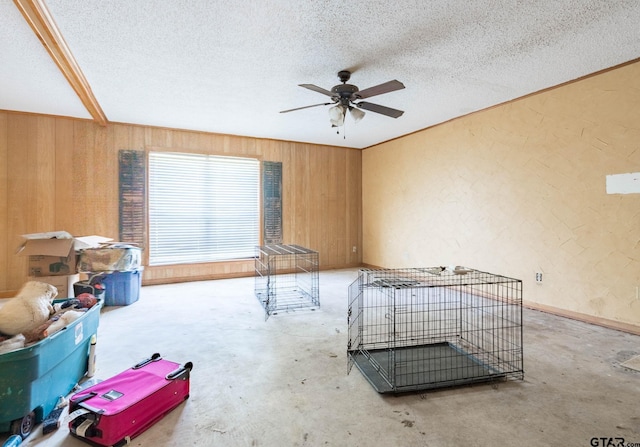310 Windridge Rd, Palestine, TX 75801 - spare room with ceiling fan, wood walls, a textured ceiling, unfinished concrete flooring, and a textured wall